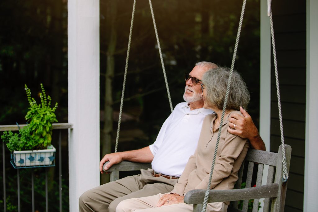 An older couple sits on a porch swing