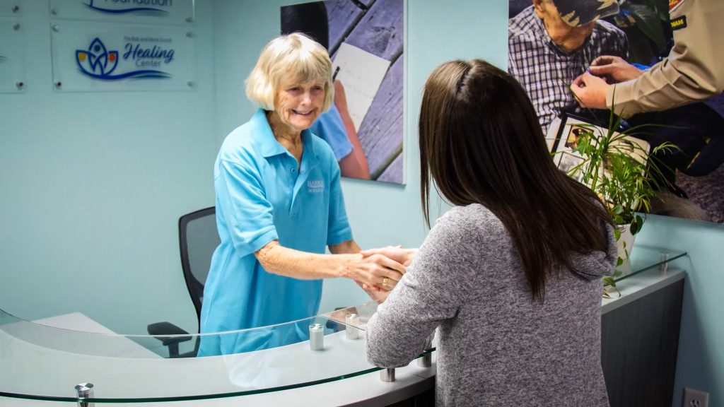 Harbor Hospice receptionist shakes hands with a woman at the front desk