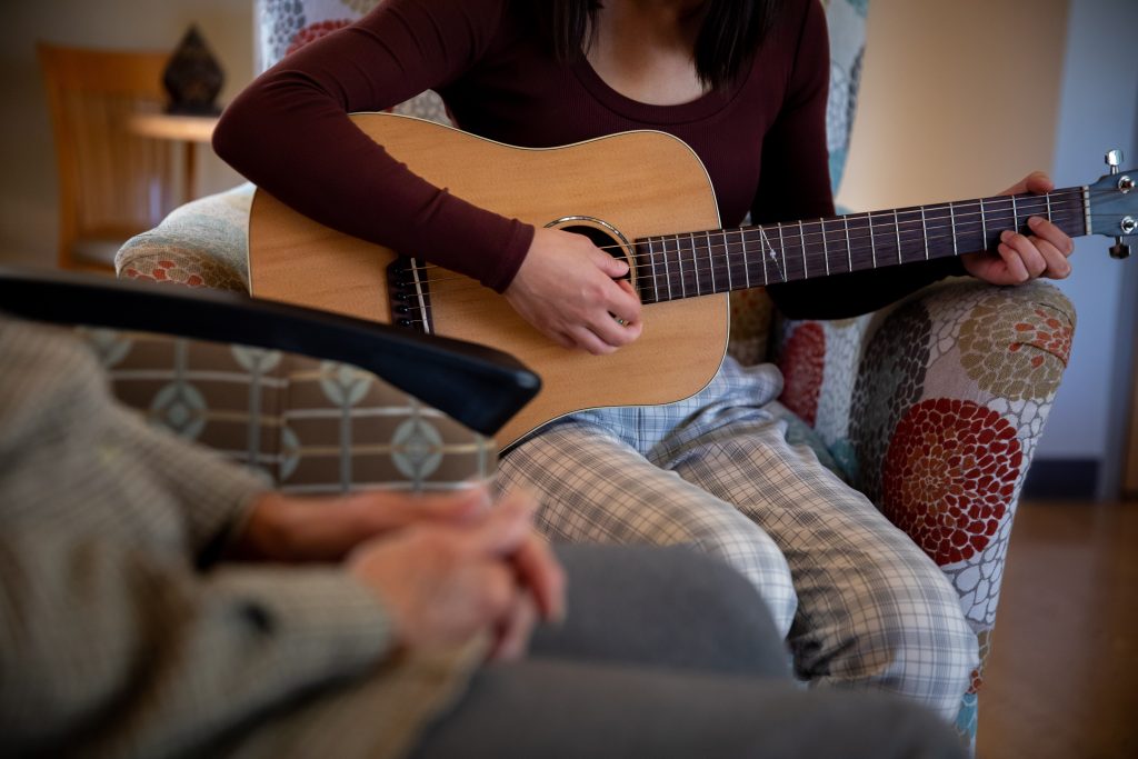 Music therapist plays the guitar with a Harbor Hospice patient