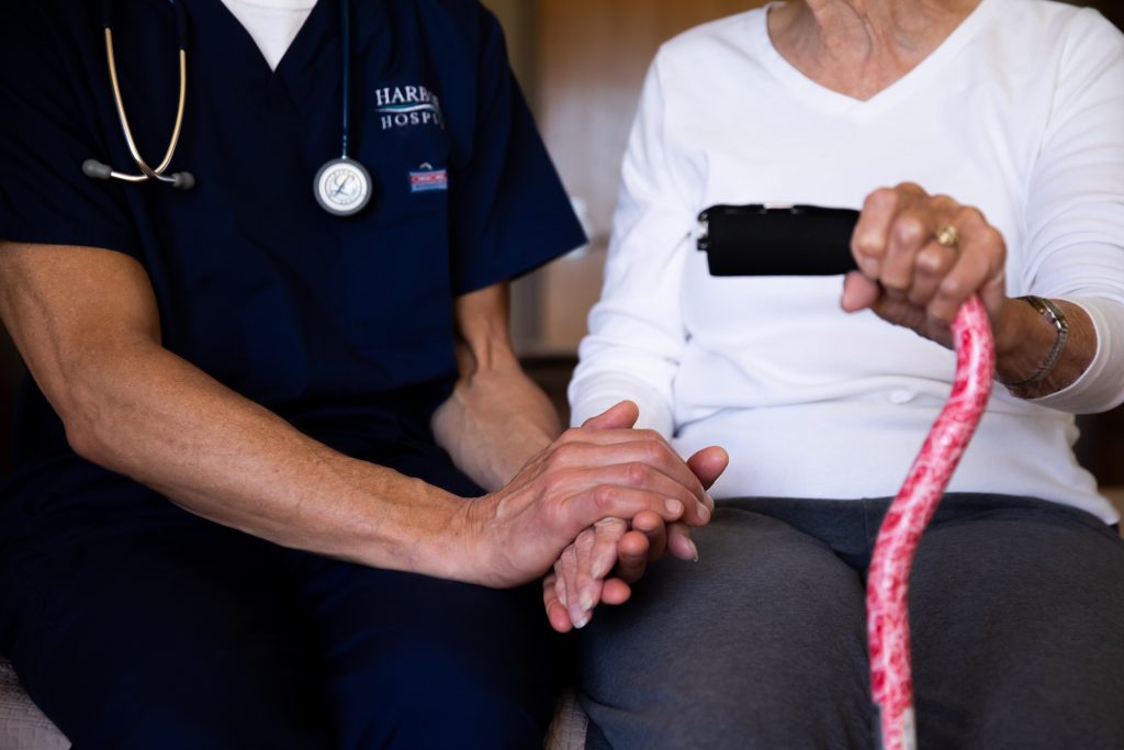 Harbor Hospice nurse holding elderly hospice patient's hand