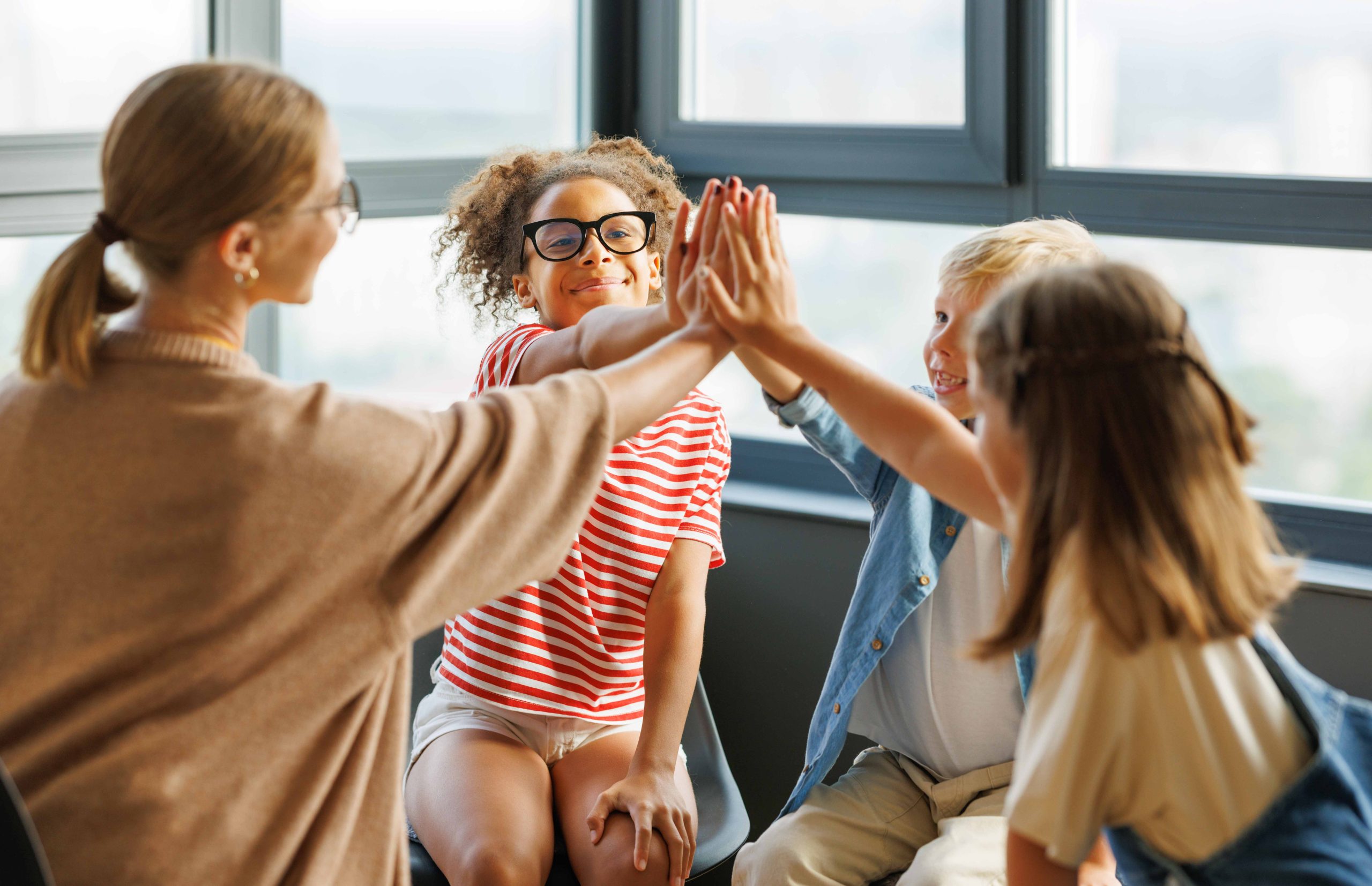 kids standing in a circle with hands together in the air